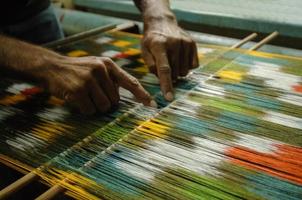 tecelagem e fabricação de tapetes artesanais closeup. as mãos do homem atrás de um tear foto