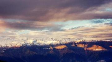 fantásticas montanhas cobertas de neve nas belas nuvens cumulus. foto