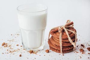 copo transparente de leite e biscoitos em um fundo branco foto