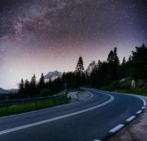 céu estrelado sobre as montanhas. a estrada de asfalto foto