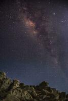 galáxia deslumbrante da via láctea sobe acima das rochas à noite foto