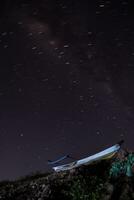 trilhas de estrelas deslumbrantes sobem acima do barco à noite foto