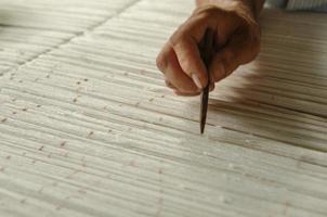mão com um lápis faz marcas no tapete. tecelagem e fabricação de tapetes artesanais closeup foto