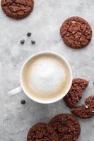 café e biscoitos. aveia, biscoitos saudáveis e xícara de café com espuma de leite, conceito de café da manhã. foto