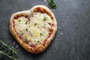 pizza caseira em forma de coração com massa de fermento e queijo para o dia dos namorados em fundo escuro. espaço de cópia da vista superior foto