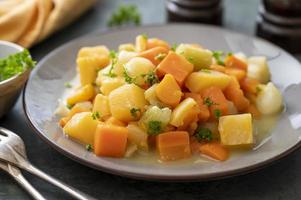 vegetais de raiz assados ou assados com ervas frescas, legumes laranja no prato. comida vegana.