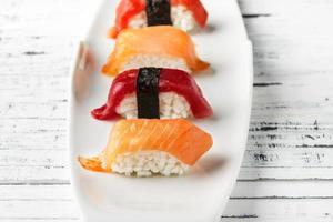 conjunto de nigiris de salmão e atum vermelho na chapa branca sobre madeira branca velha. peixe cru em estilo tradicional de sushi japonês. imagem horizontal. foto