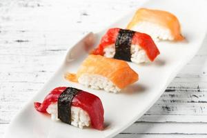 conjunto de nigiris de salmão e atum vermelho na chapa branca sobre madeira branca velha. peixe cru em estilo tradicional de sushi japonês. imagem horizontal. foto