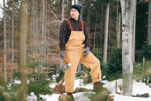 retrato de um lenhador de homem com um machado nas mãos em um fundo de floresta e árvores foto