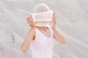 mulher loira no deserto com peixinho dourado nas mãos foto