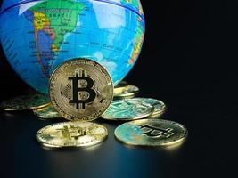 moedas bitcoin colocadas à frente de um mundo modelo em um fundo preto foto