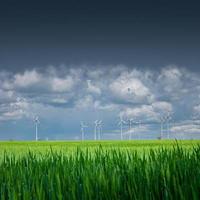 banner com bela paisagem de fazenda de campo de trigo verde e turbinas eólicas para produzir energia verde na alemanha, primavera, no céu chuvoso azul dramático e dia ensolarado, copie o fundo gradiente do espaço. foto