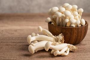 shimeji, cogumelos bunapi brancos frescos da Ásia em uma tigela de madeira. foto