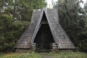 velha casa de madeira no lago da floresta de outono nos cárpatos foto