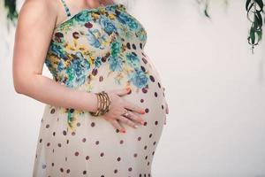 mulher grávida em um lindo vestido. concentre-se no abdômen. foto