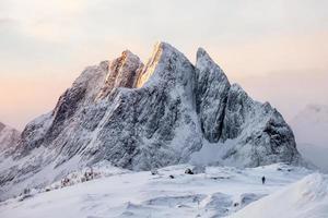 majestosa montanha nevada com alpinista na colina de neve ao nascer do sol foto