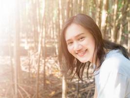 sorrindo mulheres asiáticas tirando fotos enquanto vai de férias. na floresta onde os manguezais são densamente cobertos de árvores, mas quando há luz suficiente para passar, é perfeito.