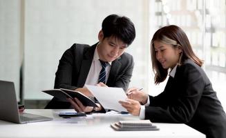 dois mulher de negócios asiáticos e empresário trabalham juntos para fazer o trabalho no escritório. foto