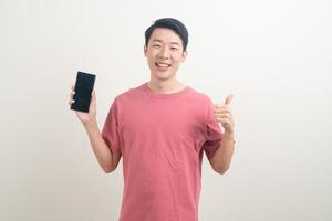 jovem asiático usando ou falando smartphone e celular com uma cara feliz foto
