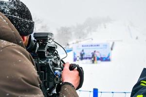 competição de esqui de filme de operador de câmera em estância de esqui em condições extremas de frio e neve foto