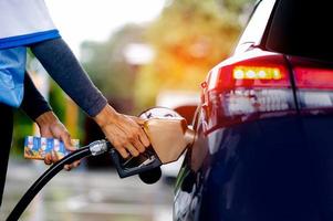 funcionários se preparam para reabastecer o carro. conceitos de transporte e industriais. encher o carro. insira a válvula de reabastecimento no gargalo de reabastecimento. foto