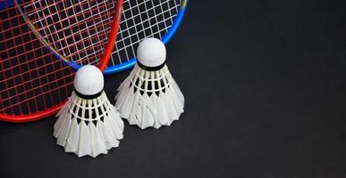petecas de badminton branco creme e raquetes no chão preto na quadra de badminton indoor, copie o espaço. foto