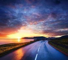 estrada de asfalto ao longo do mar ao pôr do sol na Islândia foto