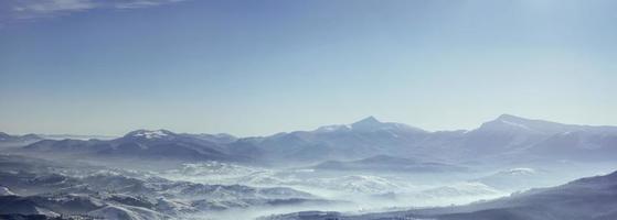 picos de montanhas nevadas com névoa em dia ensolarado. cárpato foto