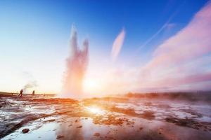 fantástica erupção do gêiser strokkur do pôr do sol na islândia. foto