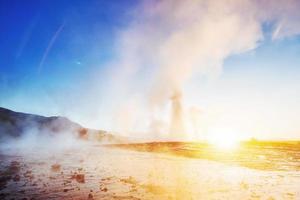 fantástica erupção do gêiser strokkur do pôr do sol na Islândia foto