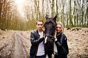 jovem casal elegante apaixonado perto de cavalo na floresta de outono. foto