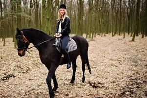 jovem loira elegante montando cavalos na floresta de outono. foto