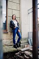 retrato de jovem elegante usar jaqueta de couro e jeans rasgados nas ruas da cidade. estilo de modelo de moda de rua. foto