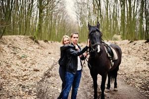 jovem casal elegante apaixonado perto de cavalo na floresta de outono. foto