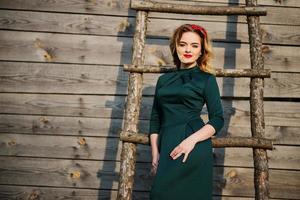 yong elegância loira na escada de madeira de fundo de vestido verde. foto