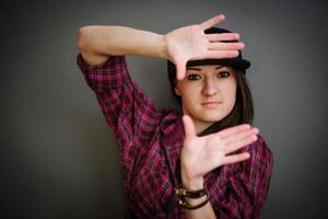 retrato de menina morena com boné vestindo parede cinza de fundo de roupas casuais. foto