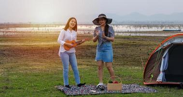 um grupo de amigos asiáticos tocando ukelele e passando o tempo fazendo um piquenique nas férias de verão. eles são felizes e se divertem nos feriados. foto