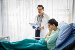 os médicos estão perguntando e explicando sobre a doença a uma paciente do sexo feminino deitada na cama em um hospital. foto