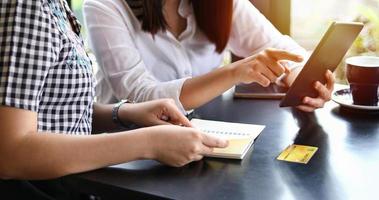 duas mulheres asiáticas tomando café em um café e fazendo compras online em telefones inteligentes foto