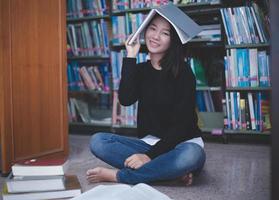 estudantes asiáticas lendo livros e usando o notebook na biblioteca. foto