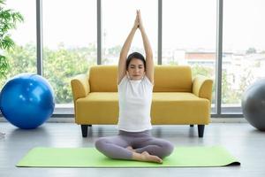 mulher asiática ioga exercitando em casa foto