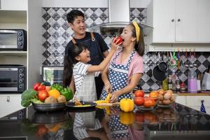 família feliz tem pai, mãe e sua filha cozinhando juntos na cozinha foto