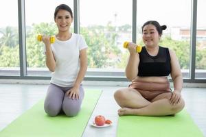 duas mulheres asiáticas se exercitando com halteres em casa