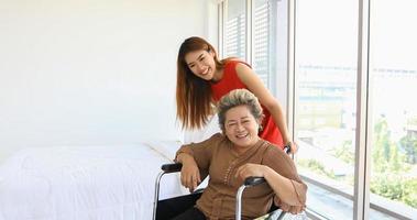 mulher alegre cuidando de sua avó em cadeira de rodas foto