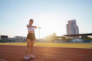 mulheres asiáticas estão assistindo o relógio esportivo ou relógio inteligente para correr na pista do estádio - estilo de vida saudável e conceitos esportivos foto