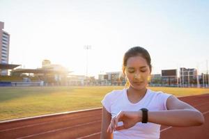 mulheres asiáticas estão assistindo o relógio esportivo ou relógio inteligente para correr na pista do estádio - estilo de vida saudável e conceitos esportivos foto