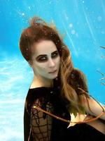 retrato de moda subaquática da bela jovem loira de vestido preto com folhas de uva foto