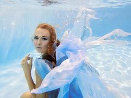 retrato de moda subaquática de mulher jovem e bonita de vestido azul foto