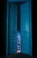 cadeira vazia na luz atrás de portas vintage maciças azuis internas. conceito de interior antiquado foto