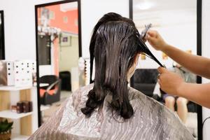 cabeleireiro profissional fazendo uma coloração e tratamento de cabelo na loja de beleza e salão de beleza. mulher mudando a cor do cabelo na loja de salão profissional. foto